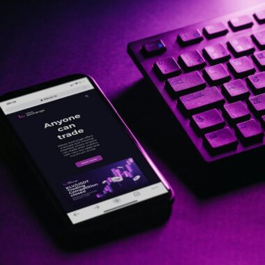 Close-up of a smartphone and keyboard with a purple hue, embodying modern technology and connectivity.