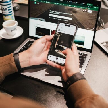 Person using a smartphone and laptop simultaneously, showcasing multitasking in technology.